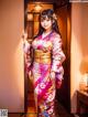 A woman in a kimono standing in front of a door.