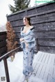 A woman in a blue and white kimono standing on a wooden deck.